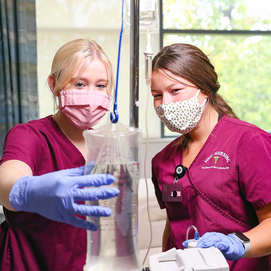 Missouri State nursing students examining an IV bag. 
